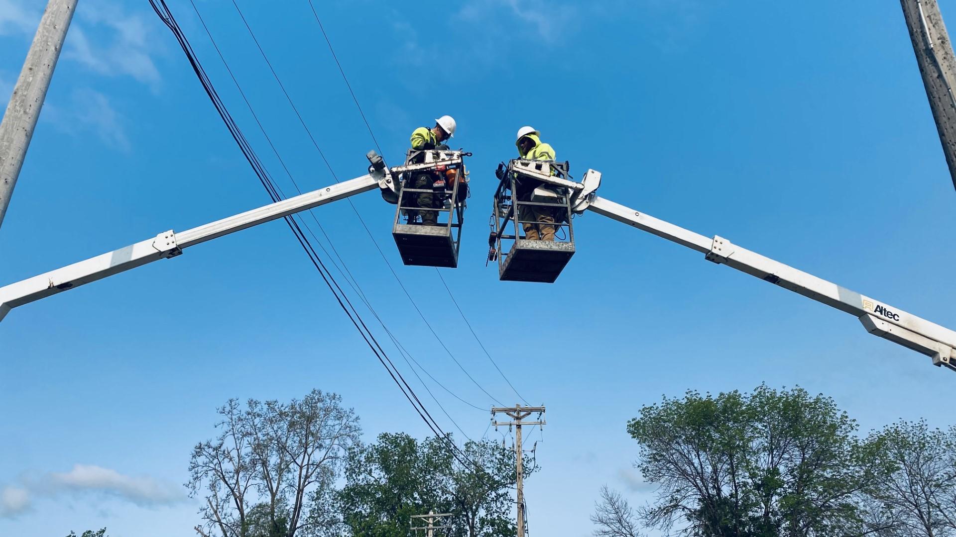 Two MCI linemen working from bucket trucks on overhead lines